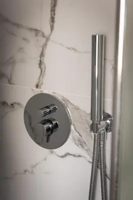 a shower with a silver knob on a marble wall at Barigelli Apartment in Rome