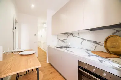 a kitchen with white cabinets and a wooden table at Barigelli Apartment in Rome