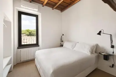 a bedroom with a white bed and a window at Casa Garibaldi, a Burghesius home in Rome