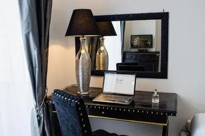 a laptop on a desk with a lamp and a mirror at Romance al Colosseo in Rome