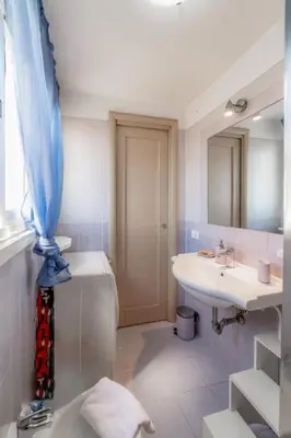 a bathroom with a sink and a toilet and a mirror at Cozy Penthouse with Terrace and Rome View in Rome