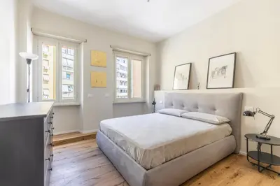 a white bedroom with a bed and two windows at La Dolce Vita - Trastevere Station in Rome