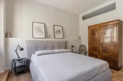 a bedroom with a white bed and a wooden cabinet at La Dolce Vita - Trastevere Station in Rome