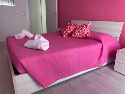 a bedroom with a pink bed with towels and pillows at Dany & Manu House in Rome