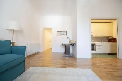 a living room with a blue couch and a kitchen at Bright and Lovely Apartment in San Lorenzo in Rome