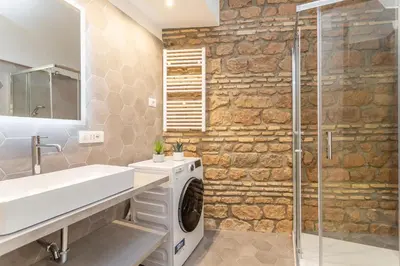 a bathroom with a washer and dryer next to a stone wall at Pantheon Giovanni Hideaway in Rome