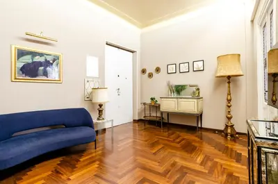 a living room with a blue couch and wooden floors at AMOE - Eleganza e Storia nel Cuore di Roma in Rome