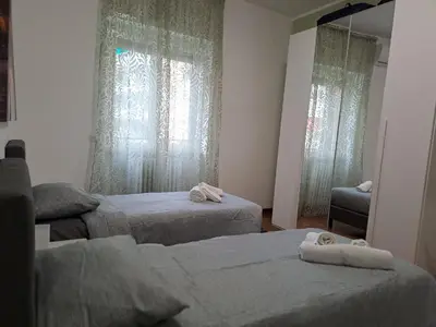 a bedroom with two beds and a window with curtains at Mauri's Home - CasaMauri - Adiacente Metro C in Rome