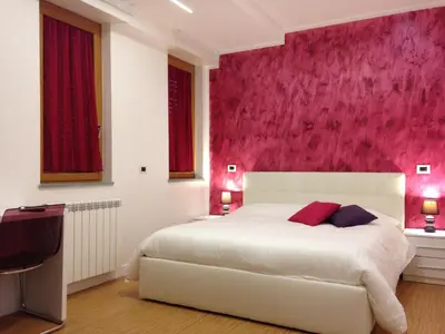 a bedroom with a white bed with a pink wall at Valle Aurelia House in Rome