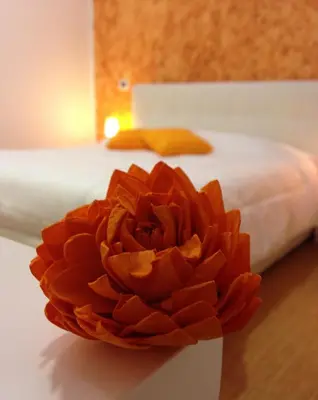 a red flower sitting on a table next to a bed at Valle Aurelia House in Rome