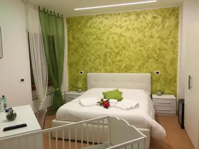 a bedroom with a white bed and a green wall at Valle Aurelia House in Rome