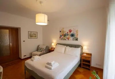 a bedroom with a white bed and a chair at Dimora al Colosseo, 2 bedrooms in Rome