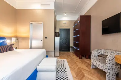 a hotel room with a bed and a chair and a tv at The Couper Umiltà in Rome