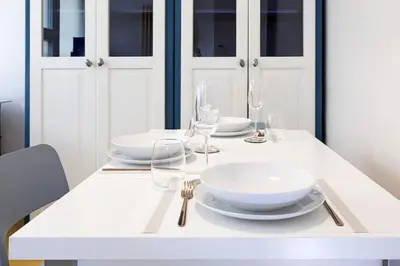 a white table with plates and glasses on it at Jubilee Penthouse by Nosdom Properties in Rome