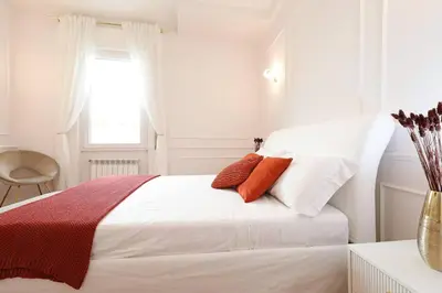 a white bedroom with a bed with red and white pillows at Jubilee Penthouse by Nosdom Properties in Rome