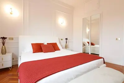 a white bedroom with a large bed with red pillows at Jubilee Penthouse by Nosdom Properties in Rome