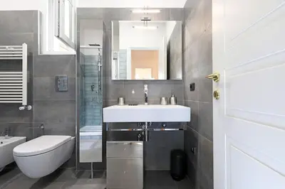 a bathroom with a sink and a toilet and a mirror at Jubilee Penthouse by Nosdom Properties in Rome