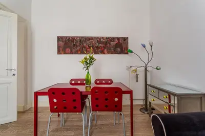 a dining room table with red chairs and a vase on it at iFlat Lina Cavalieri House in Rome
