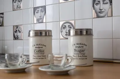 three cups of coffee on a counter with faces on the wall at iFlat Lina Cavalieri House in Rome