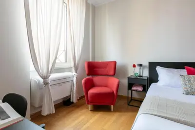 a bedroom with a red chair next to a window at Casa Acaia by Hili in Rome