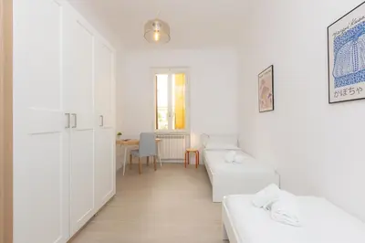 a white room with two white beds and a table at Mastai Trastevere Home by Rental in Rome in Rome