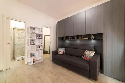 a living room with a black couch and shelves at Smart Home - Trilocale con Parcheggio Privato in Rome