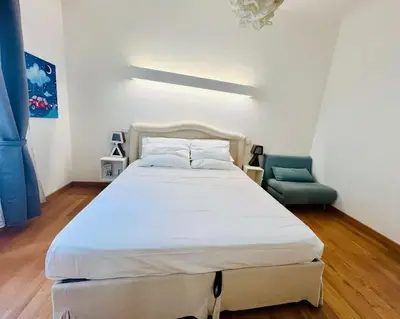 a bedroom with a white bed and a green chair at Anna Rome Vatican Luxury in Rome