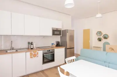 a kitchen with white cabinets and a blue couch at Alba Terrace - Rome Modern Apt Close to Metro in Rome