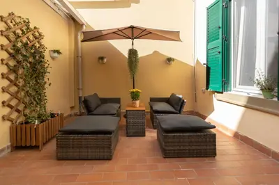 a patio with two chairs and an umbrella at Alba Terrace - Rome Modern Apt Close to Metro in Rome