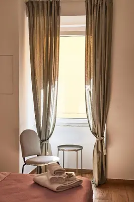 a bedroom with a bed and a window with a chair at Napodano Apartments - Roma in Rome