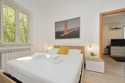a white bedroom with a large bed and a tv at Parioli Apartment self check in in Rome
