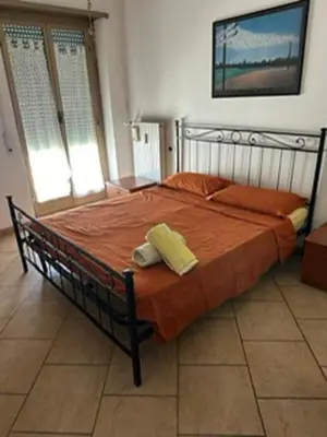a bedroom with a large bed with orange sheets at Nathan House, Malatesta in Rome