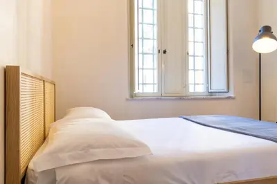 a bedroom with a bed with white sheets and a window at Apartment Next to St Peter in Rome