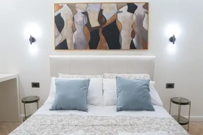 a bedroom with a white bed with two blue pillows at Maison Vaticano - A few steps from Vatican and San Peter in Rome
