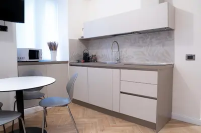 a kitchen with white cabinets and a table and a sink at Maison Vaticano - A few steps from Vatican and San Peter in Rome