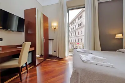 a hotel room with a bed and a desk and a window at Domus Maggiore in Rome