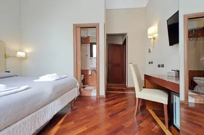 a hotel room with a bed and a desk and a bathroom at Domus Maggiore in Rome