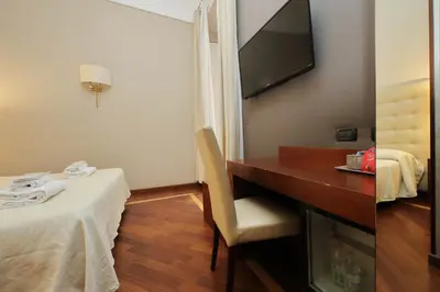 a hotel room with a desk and a television on the wall at Domus Maggiore in Rome