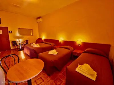 a hotel room with three beds and a table at Hotel Azzurra in Rome