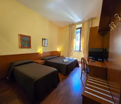 a hotel room with two beds and a television at Hotel Azzurra in Rome