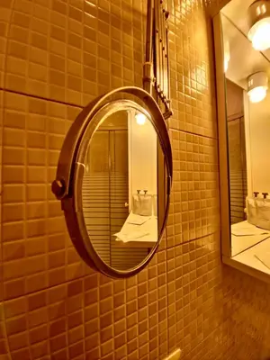 a bathroom with a round mirror on the wall at Hotel Azzurra in Rome