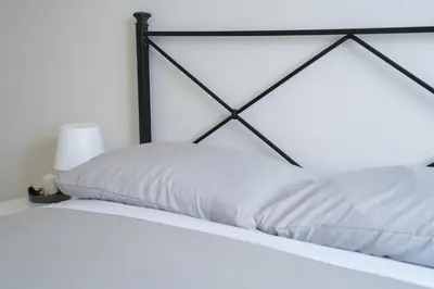 a bed with white sheets and a black frame at Vatican 4 BedRoom Apartment with Private Parking in Rome