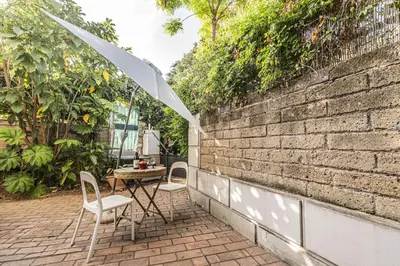 a patio with a table and chairs and an umbrella at Unique Garden Apartment near Caracalla Baths in Rome