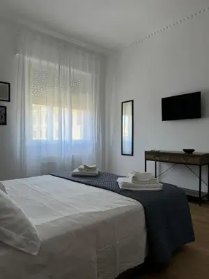 a white bedroom with a bed and a television at Casa Palmiero in Rome