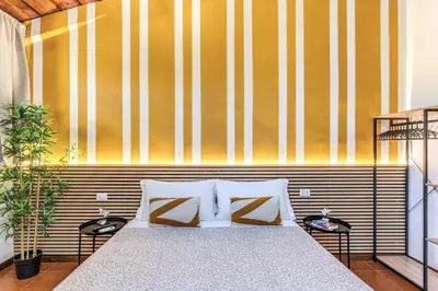 a bedroom with a bed and a yellow and white striped wall at Elena Vatican Apartment in Rome