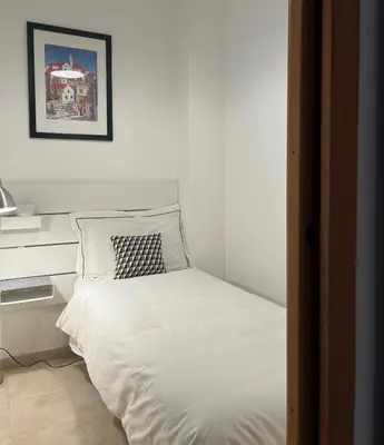 a bedroom with a white bed with a black and white pillow at Casa Roma San Giovanni in Rome