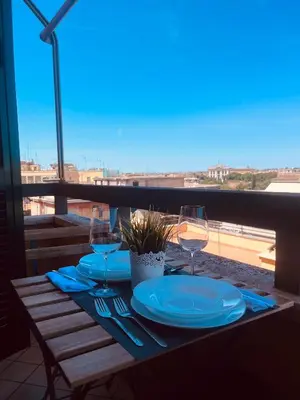 a table with plates and wine glasses on a balcony at Casa Roma San Giovanni in Rome