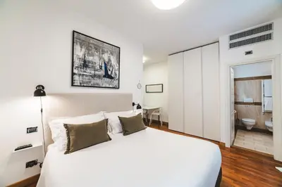 a bedroom with a large white bed and a bathroom at Elegant Apartment Vallombrosa 55 in Rome
