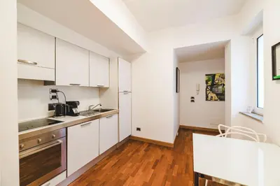 a kitchen with white cabinets and a wooden floor at Elegant Apartment Vallombrosa 55 in Rome