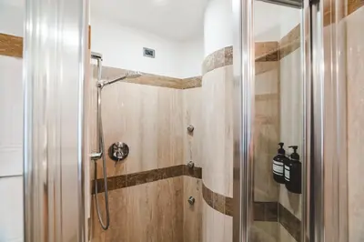 a shower in a bathroom with wooden walls at Elegant Apartment Vallombrosa 55 in Rome